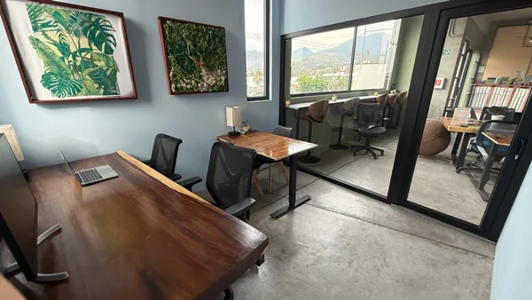 Una oficina privada, moderna y luminosa, con una gran ventana, una silla cómoda y un escritorio espacioso.